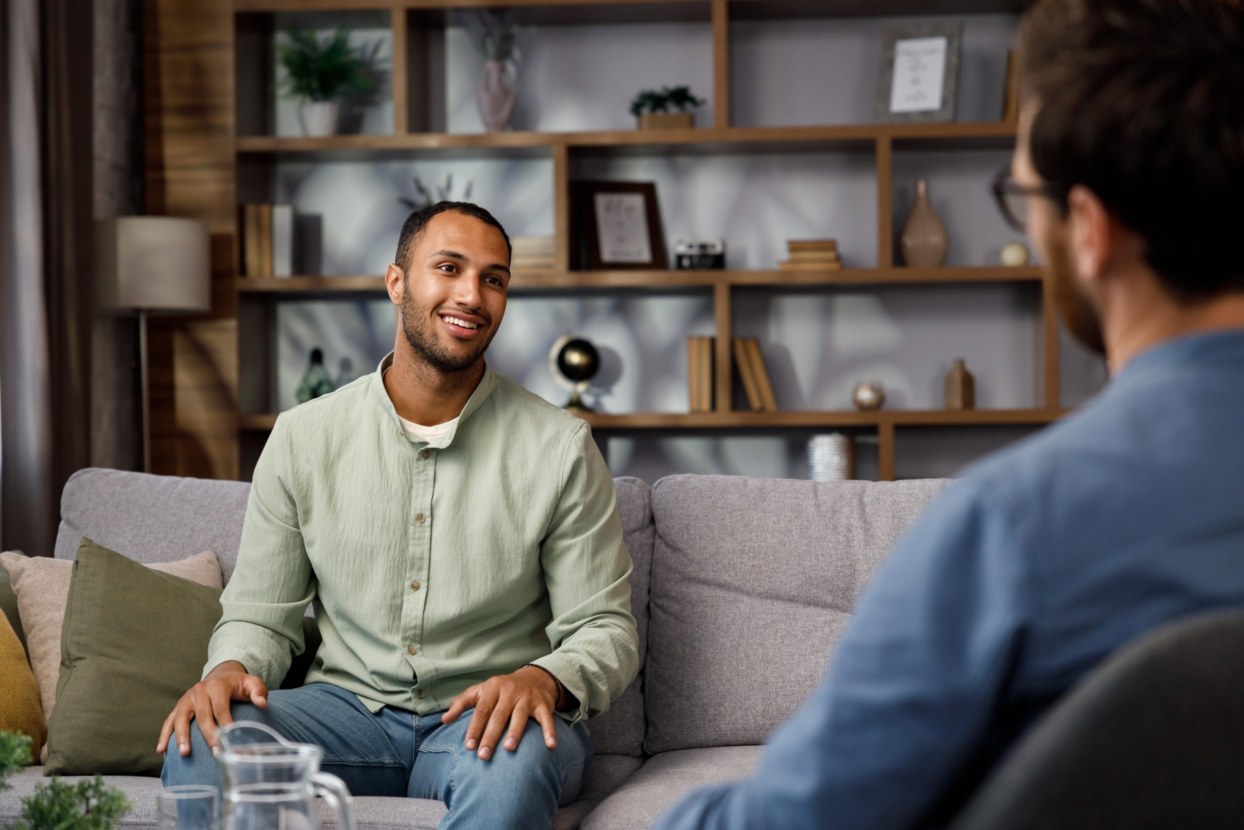 Therapist speaking with a patient during a consultation in an office with shelving and plants