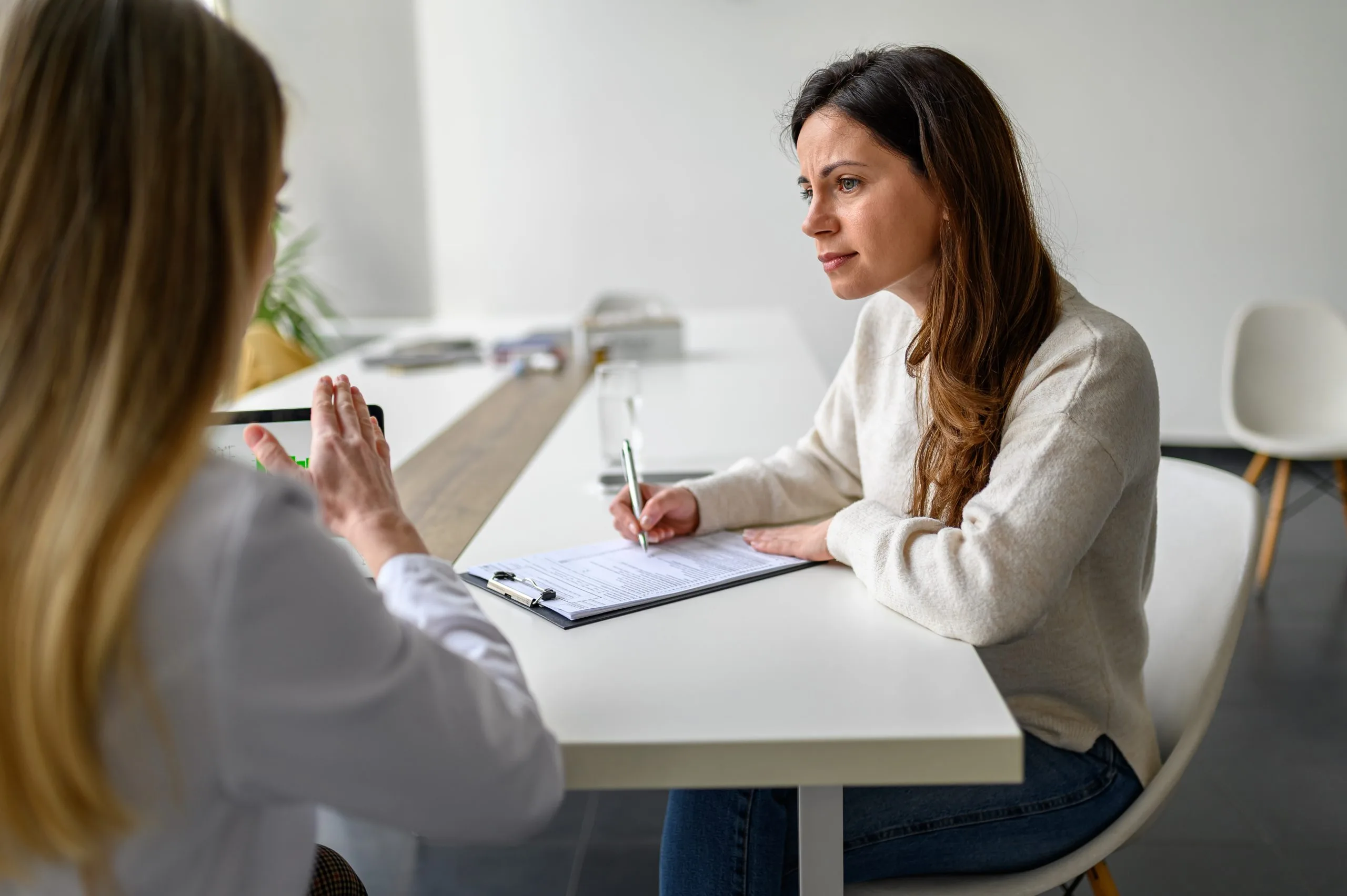 Healthcare provider taking notes during a medication management consultation with a patient