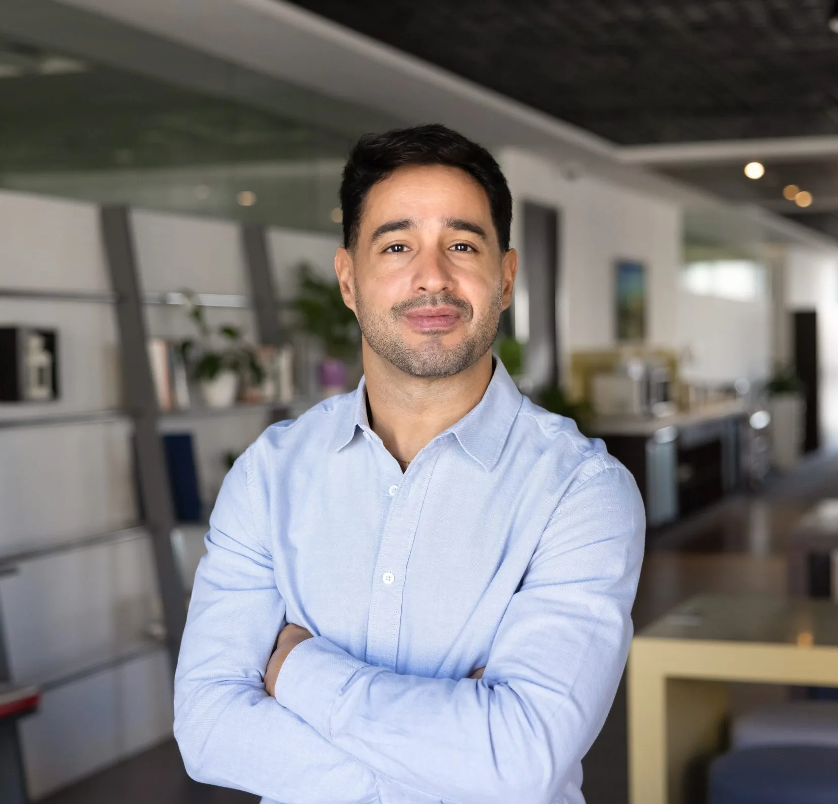 Professional man in light blue shirt standing in modern office workspace