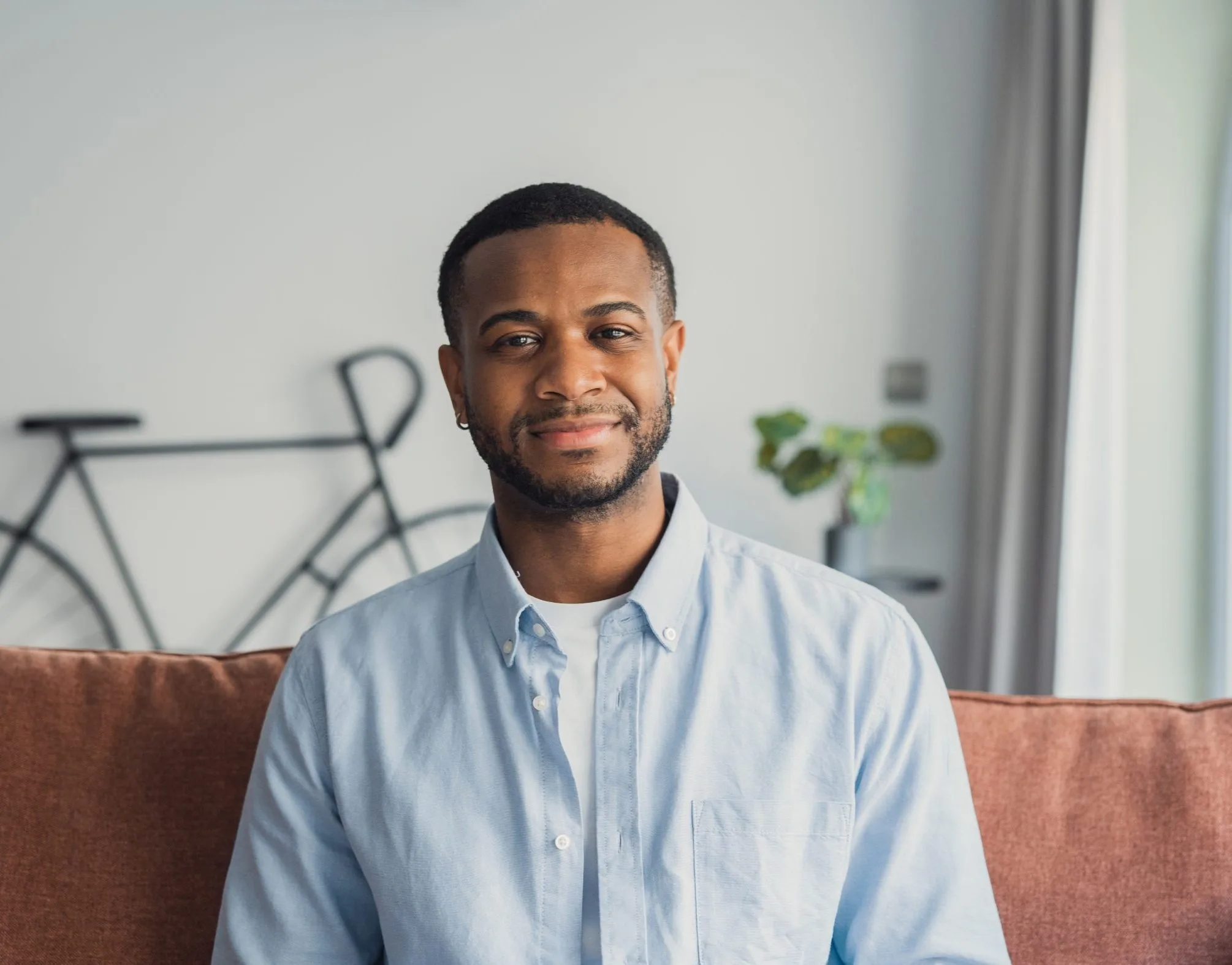 Man in light blue shirt sitting on brown couch in modern living room