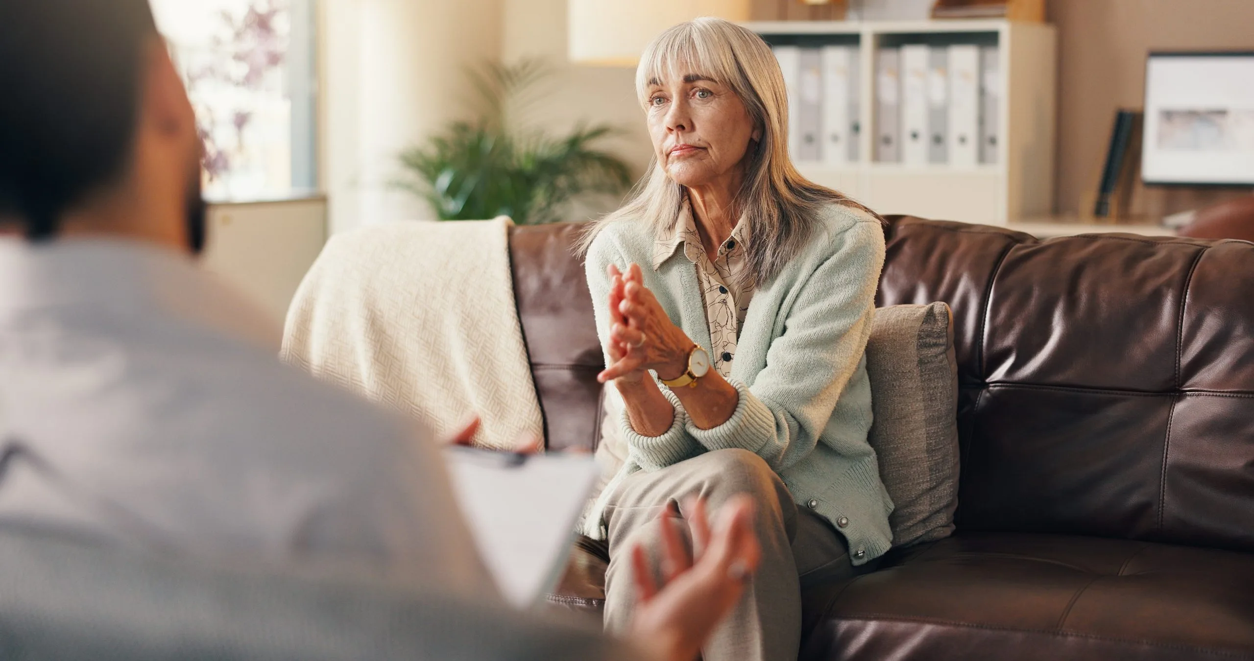 Older woman speaking with a therapist during a consultation in a clinical office setting