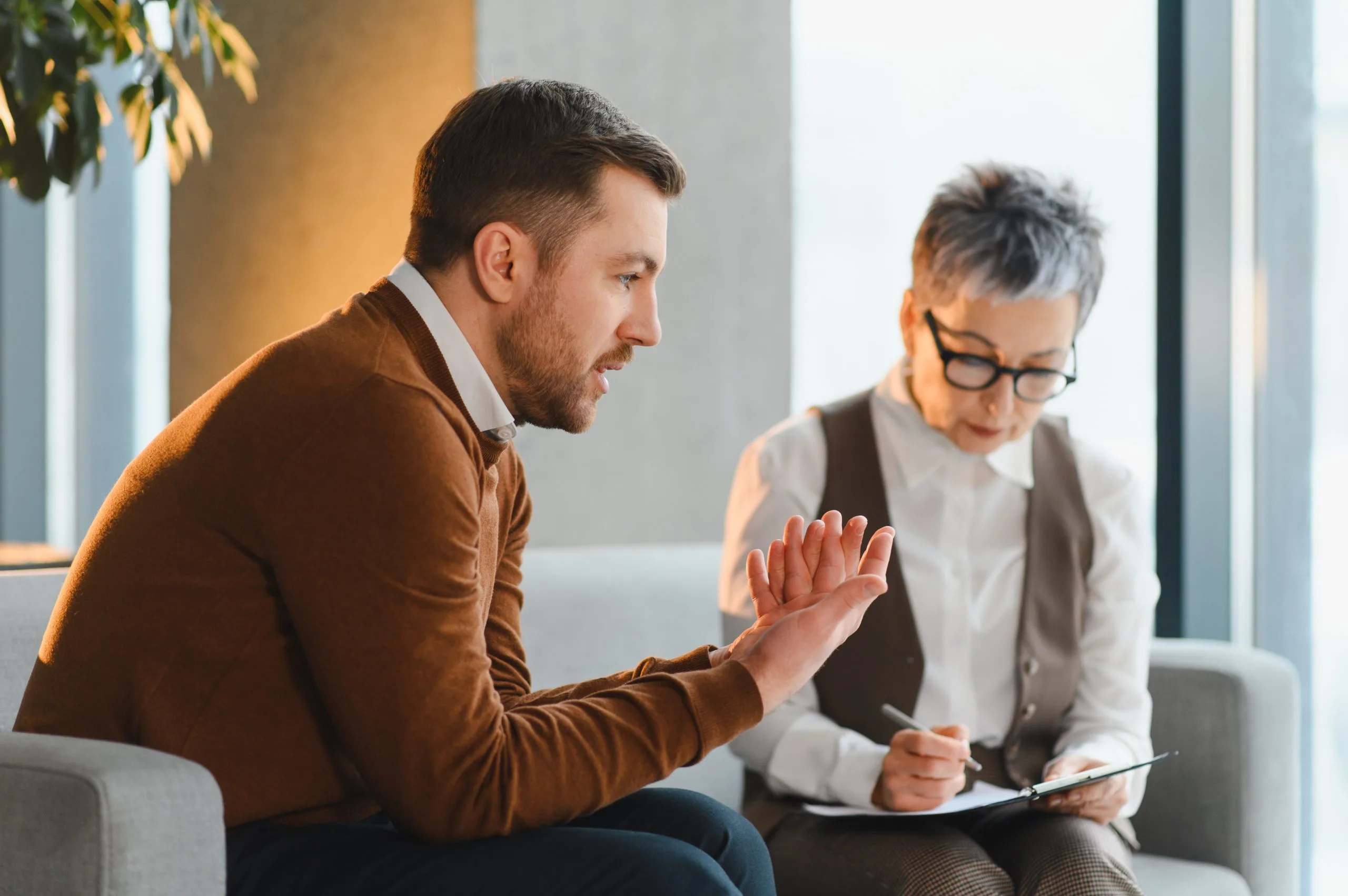 Man and woman in professional attire discussing medication management during a consultation in a bright office setting