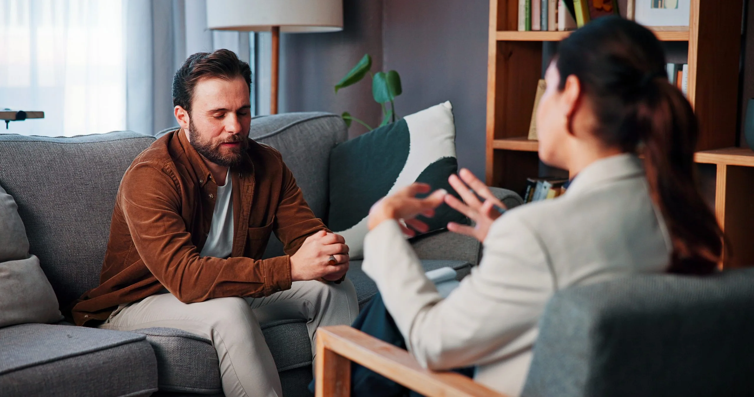 Therapist and patient having a counseling session in an office with bookshelves and plants