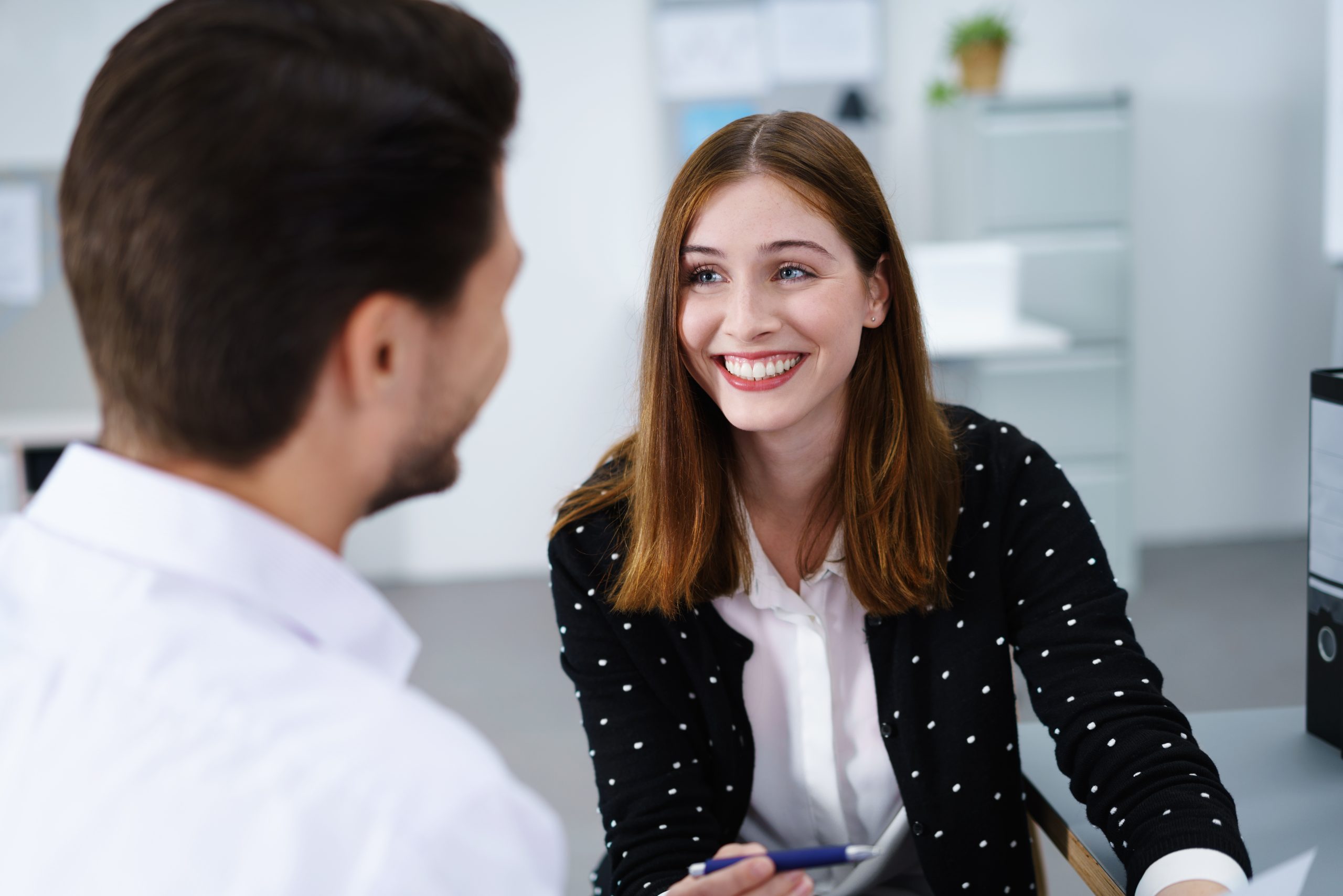 Therapist smiling while speaking with a male patient in a bright clinical office