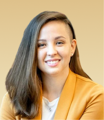 Smiling team member wearing a yellow blazer against a tan background