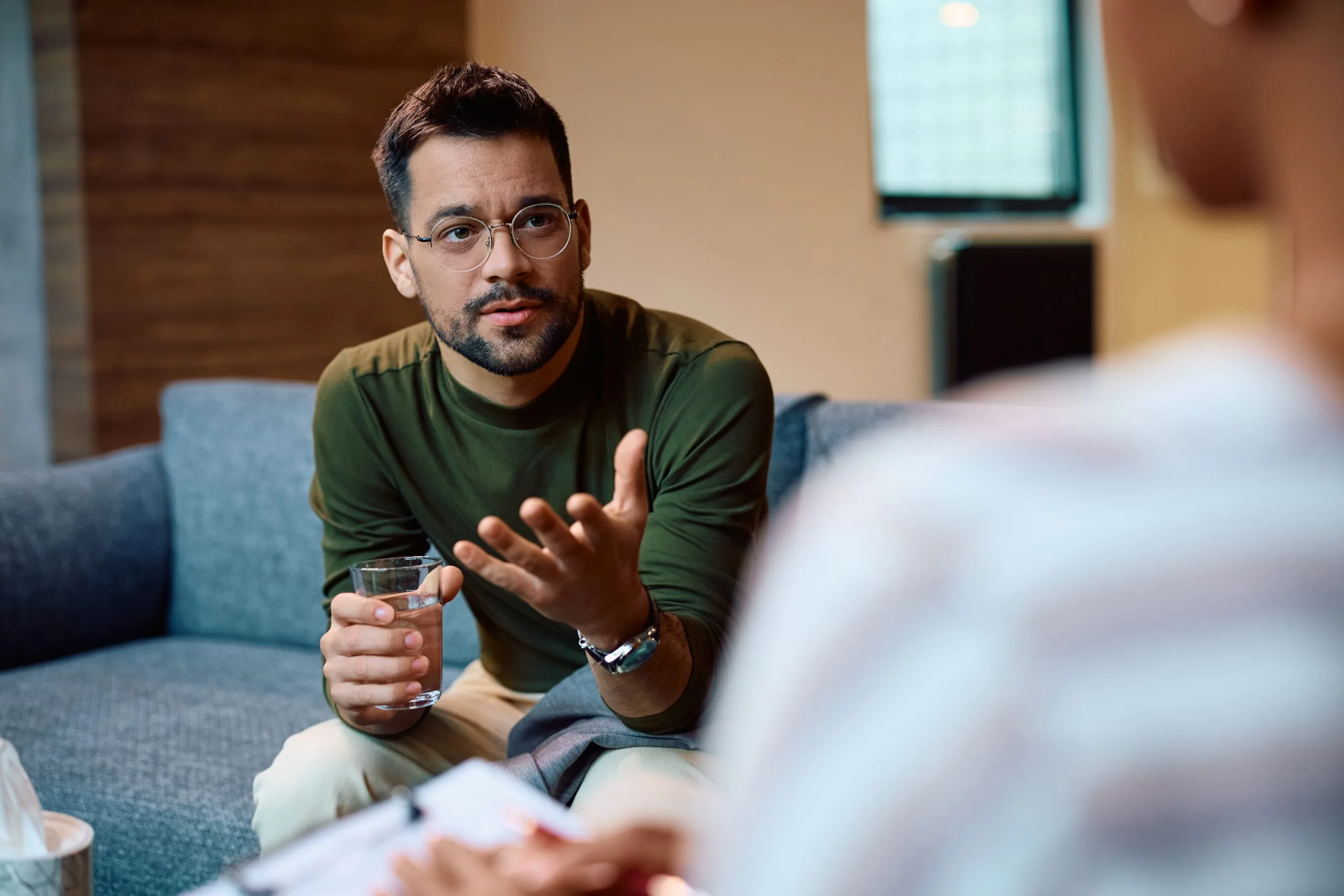 Man in green shirt speaking with gestures during a therapy conversation