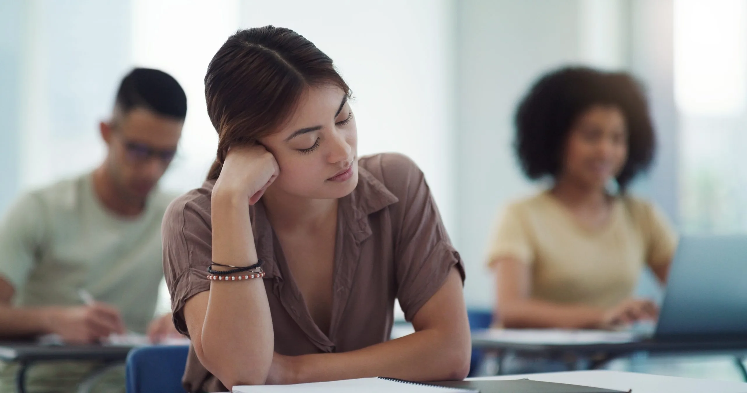Woman in thoughtful pose during a group therapy or support session with other participants in background