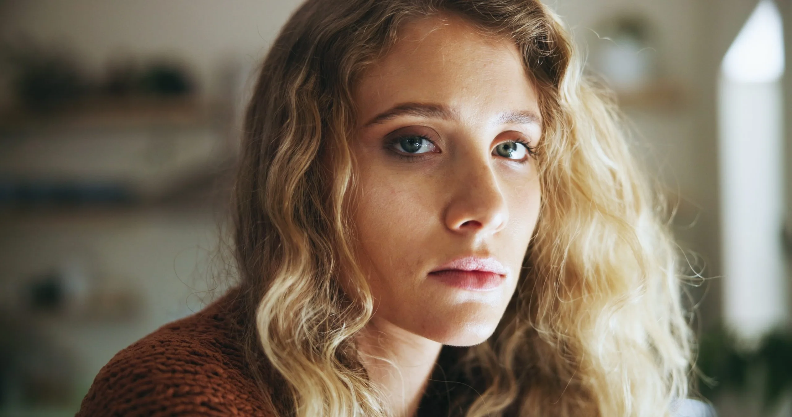 Woman with wavy blonde hair looking directly at camera with concerned expression