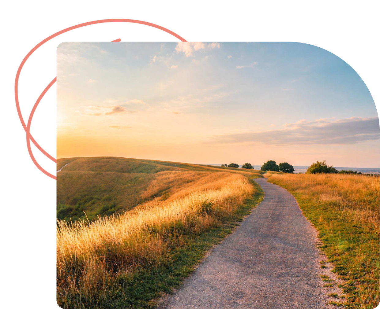 Dirt path winding through golden grassland at sunset with rolling hills and trees