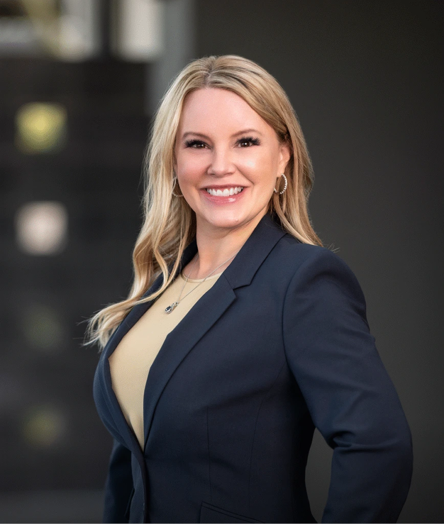Woman with blonde hair wearing dark blazer over cream top in professional portrait