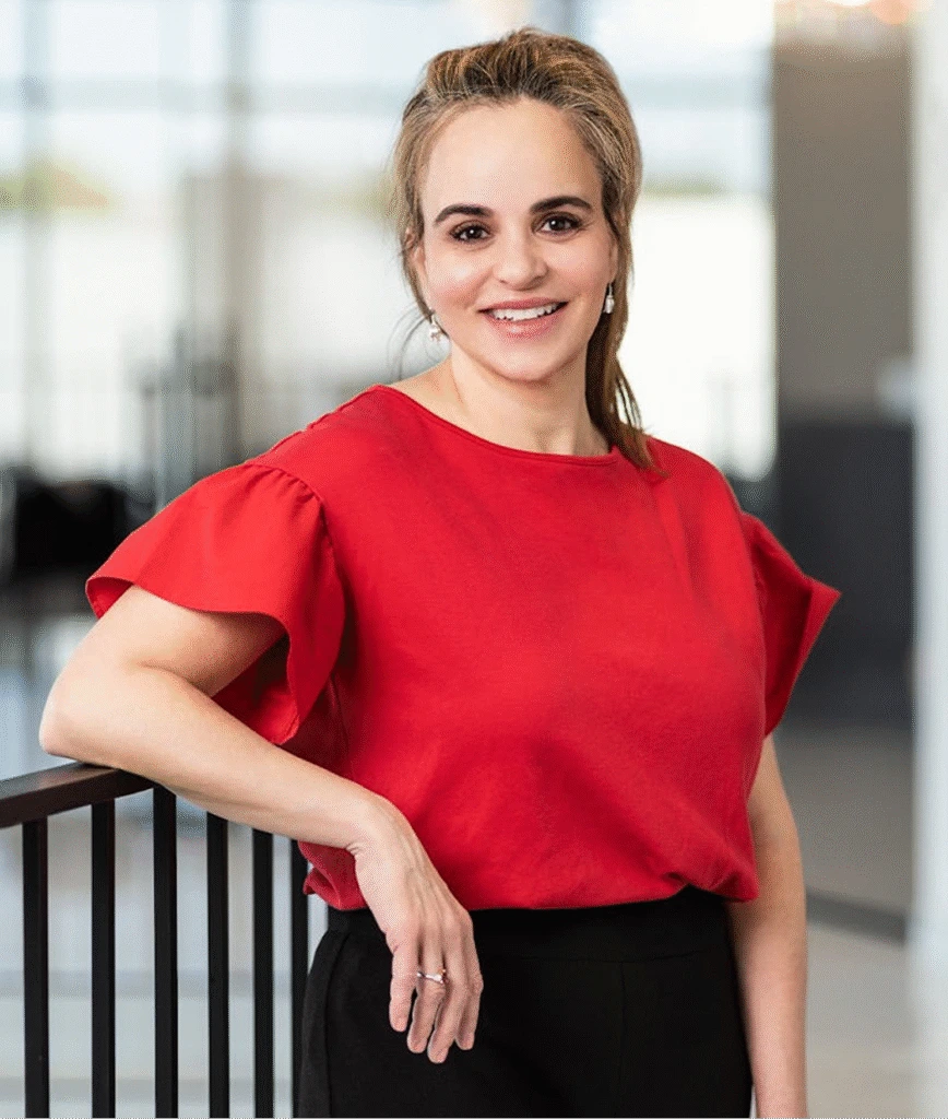 Woman in red top leaning against railing in modern office setting