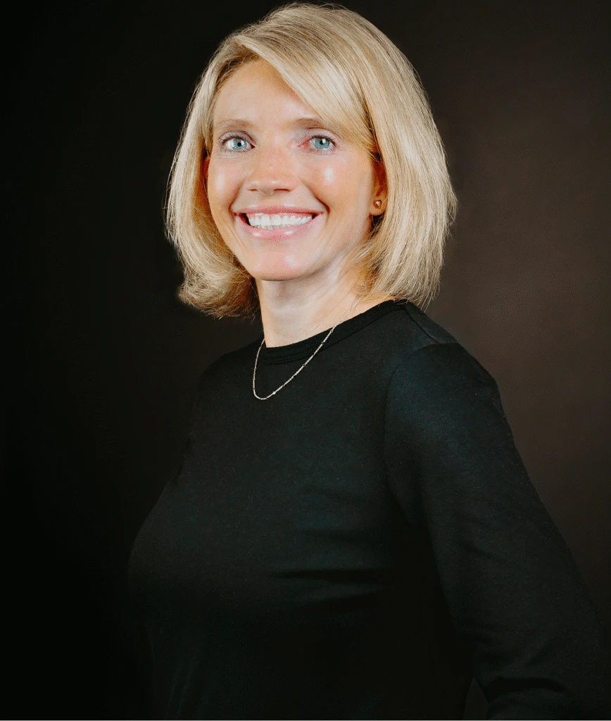 Woman with blonde hair smiling at camera in black shirt, professional portrait