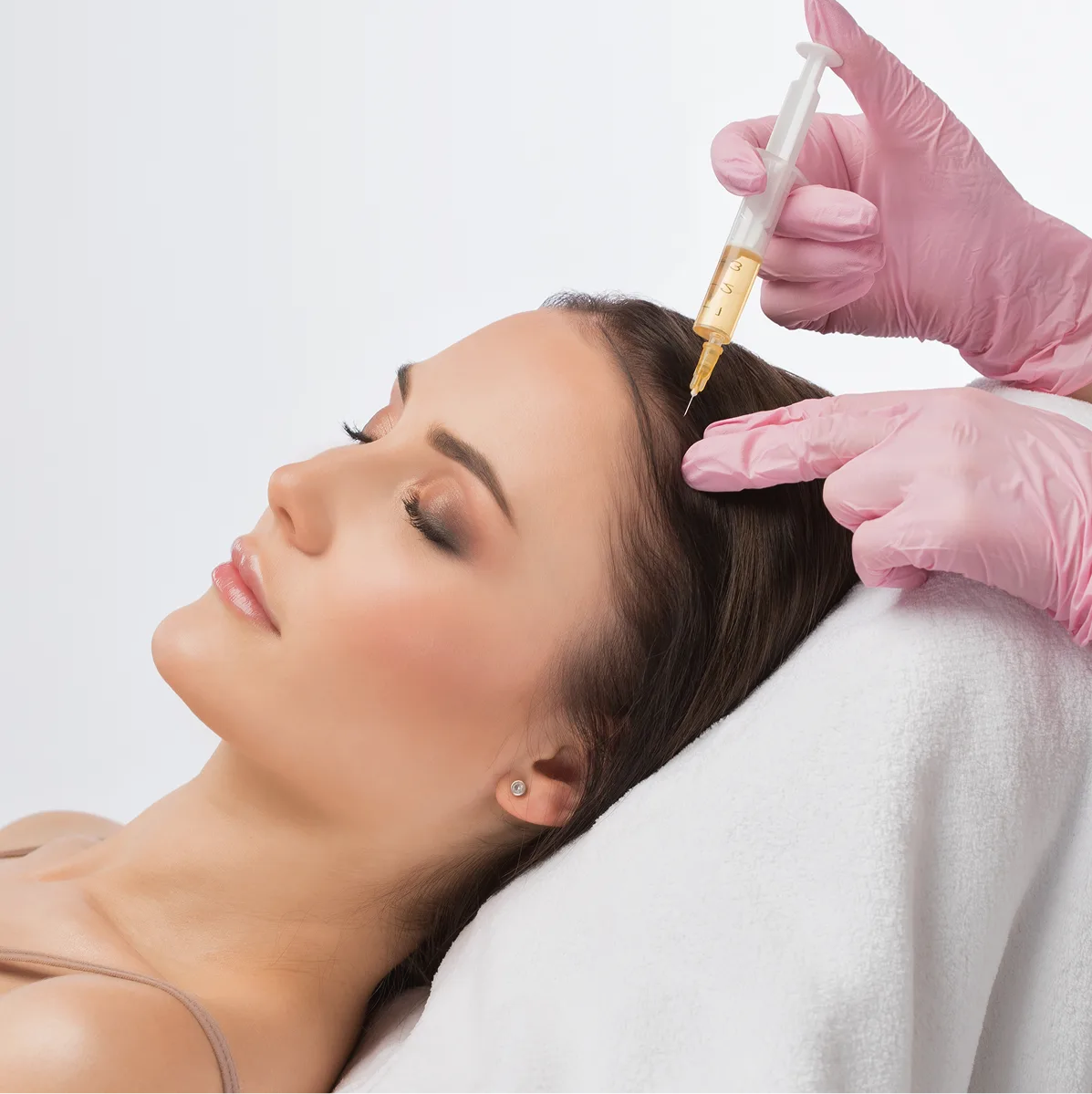 Healthcare provider in pink gloves administering PRP injection to patient's scalp