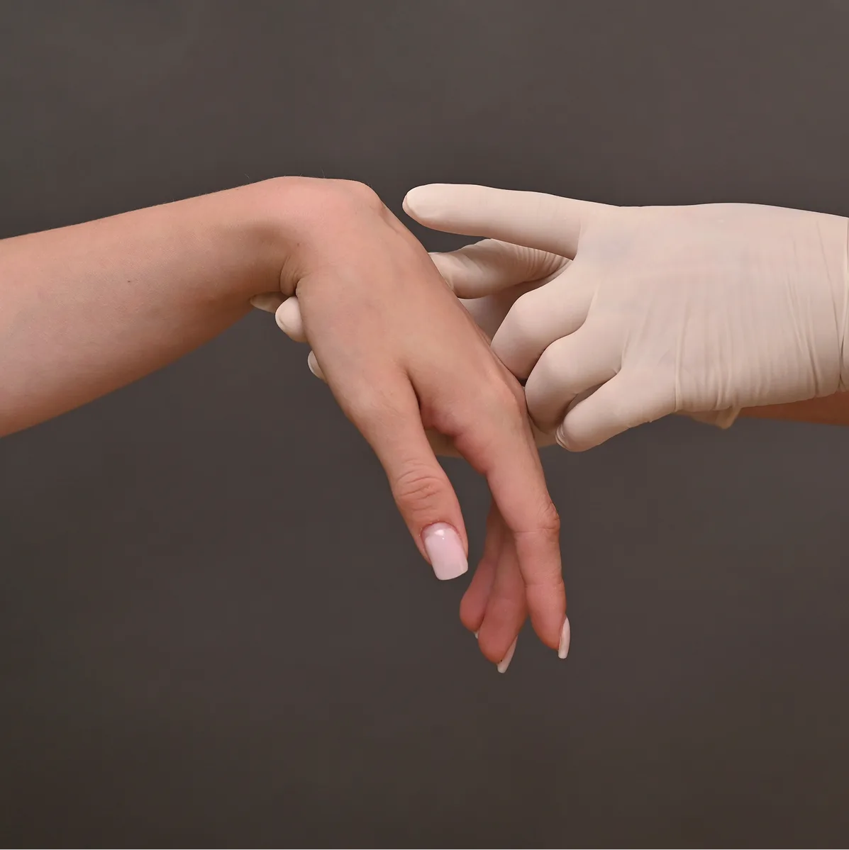 Healthcare provider in white gloves examining a patient's hand for lumps or abnormalities