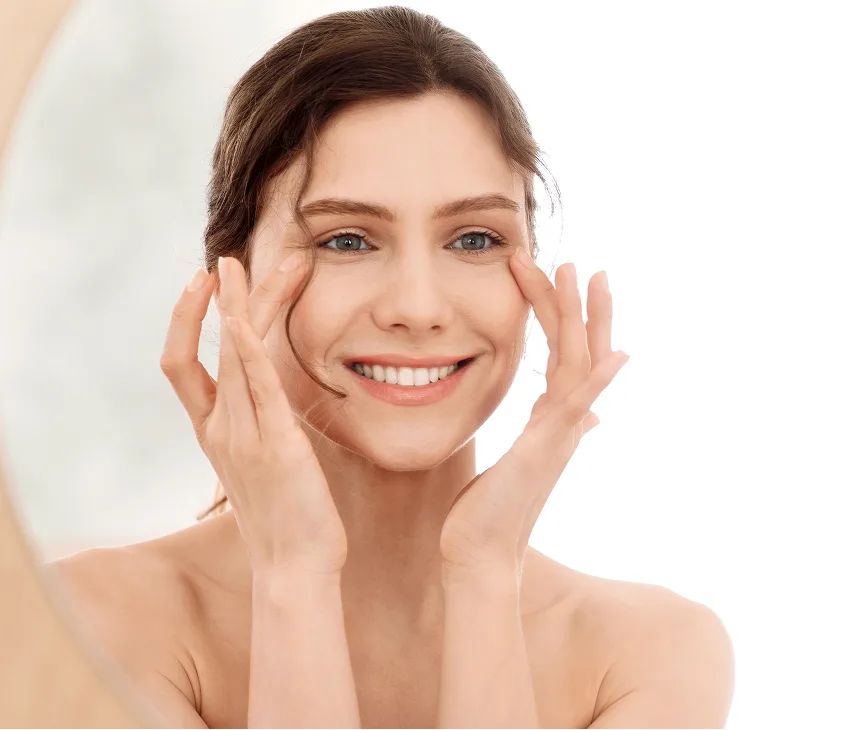 Woman smiling with hands touching her face, showing healthy skin