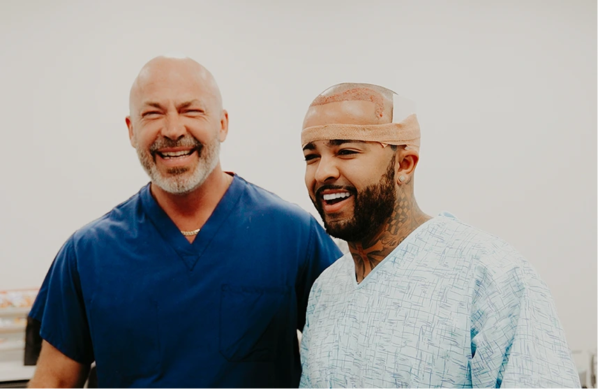 Two men smiling, one with visible hair restoration results and head wrap