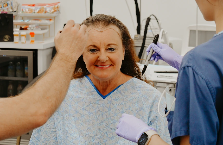 Smiling female patient receiving injectable treatment to forehead from practitioner in clinical setting