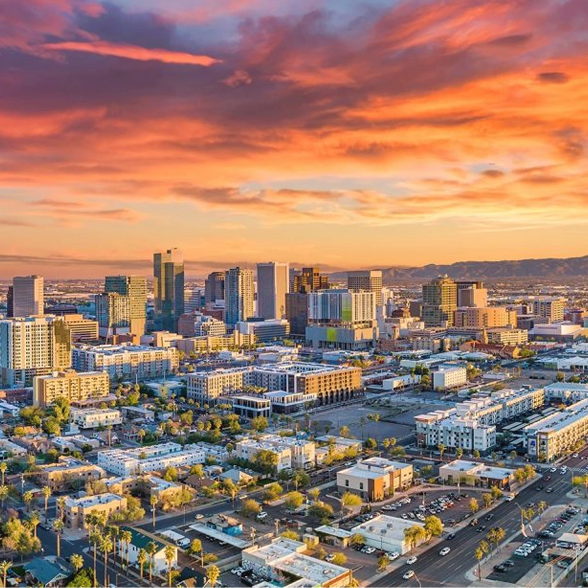 City skyline at golden hour sunset with downtown buildings and mountains