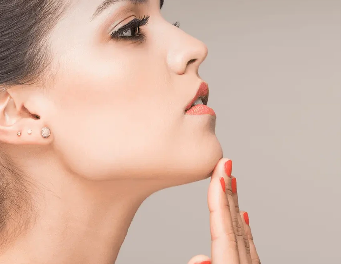 Woman in profile view touching chin with red nail polish