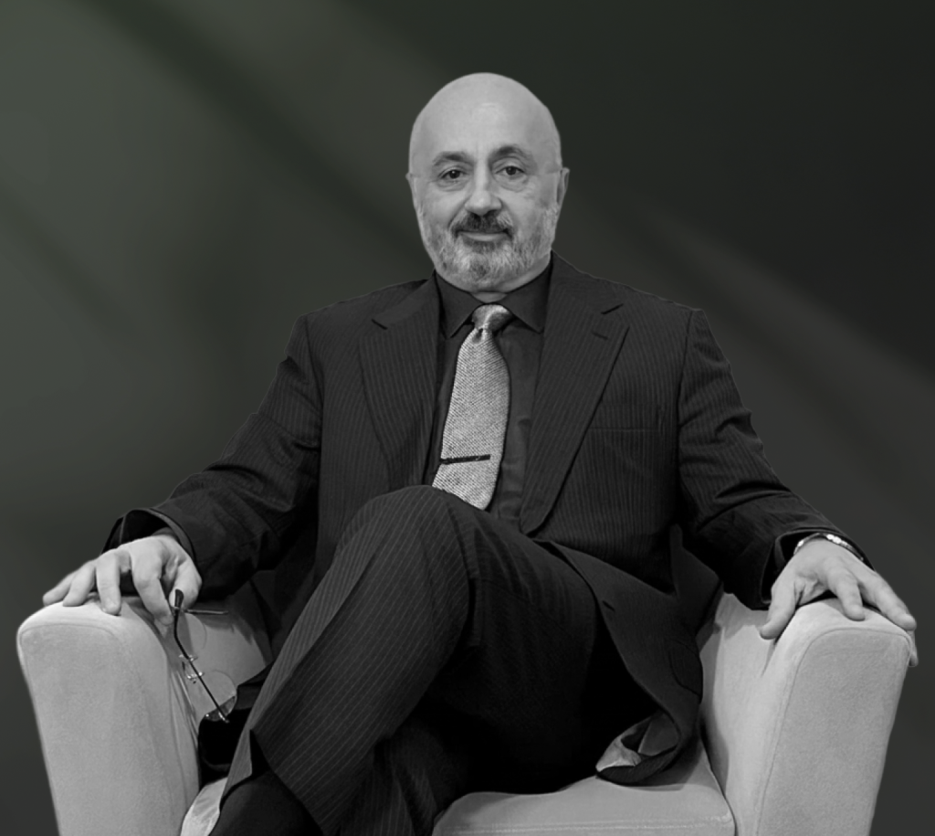 Dr. Edwin in dark pinstriped suit seated against neutral background