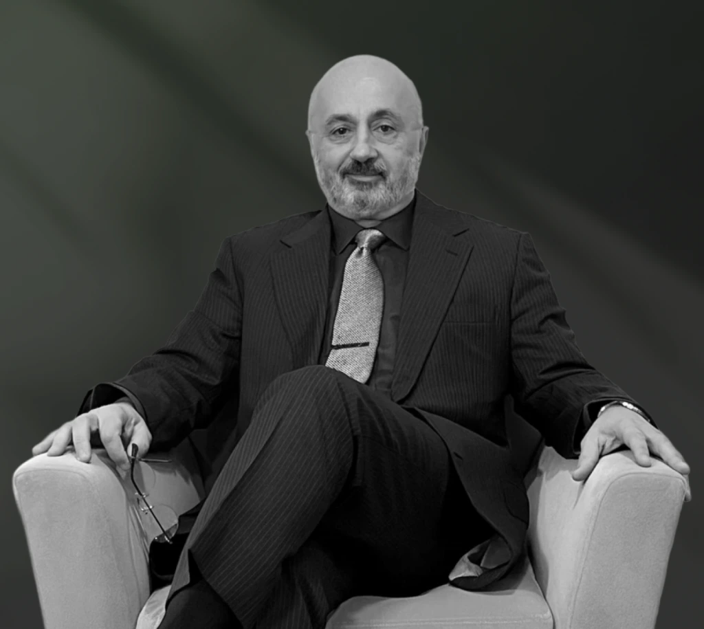 Dr. Edwin in dark pinstriped suit seated against neutral background
