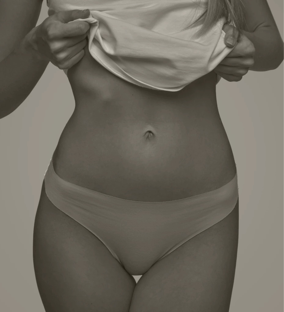 Person lifting white shirt to reveal torso and abdominal definition