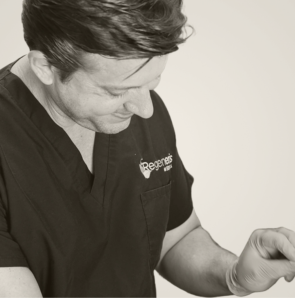 Regeneris staff member in branded black scrubs examining patient's arm