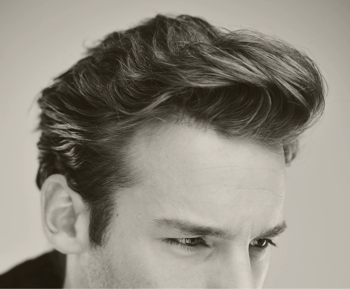 Man with voluminous styled dark hair looking downward