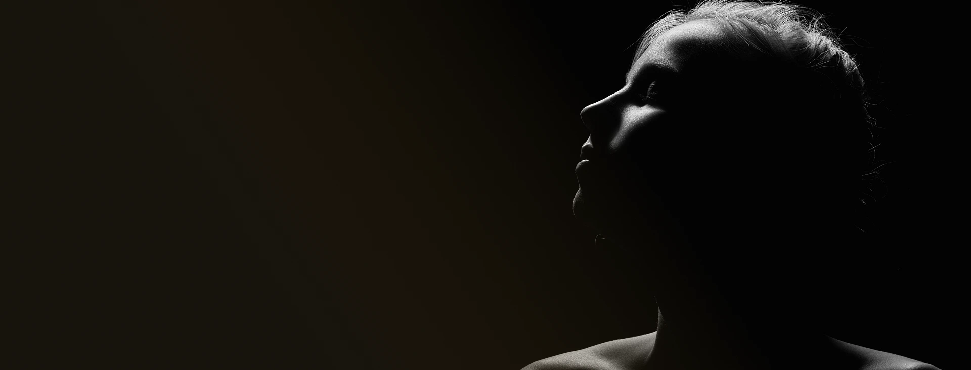 Profile silhouette of a woman's face against dark background