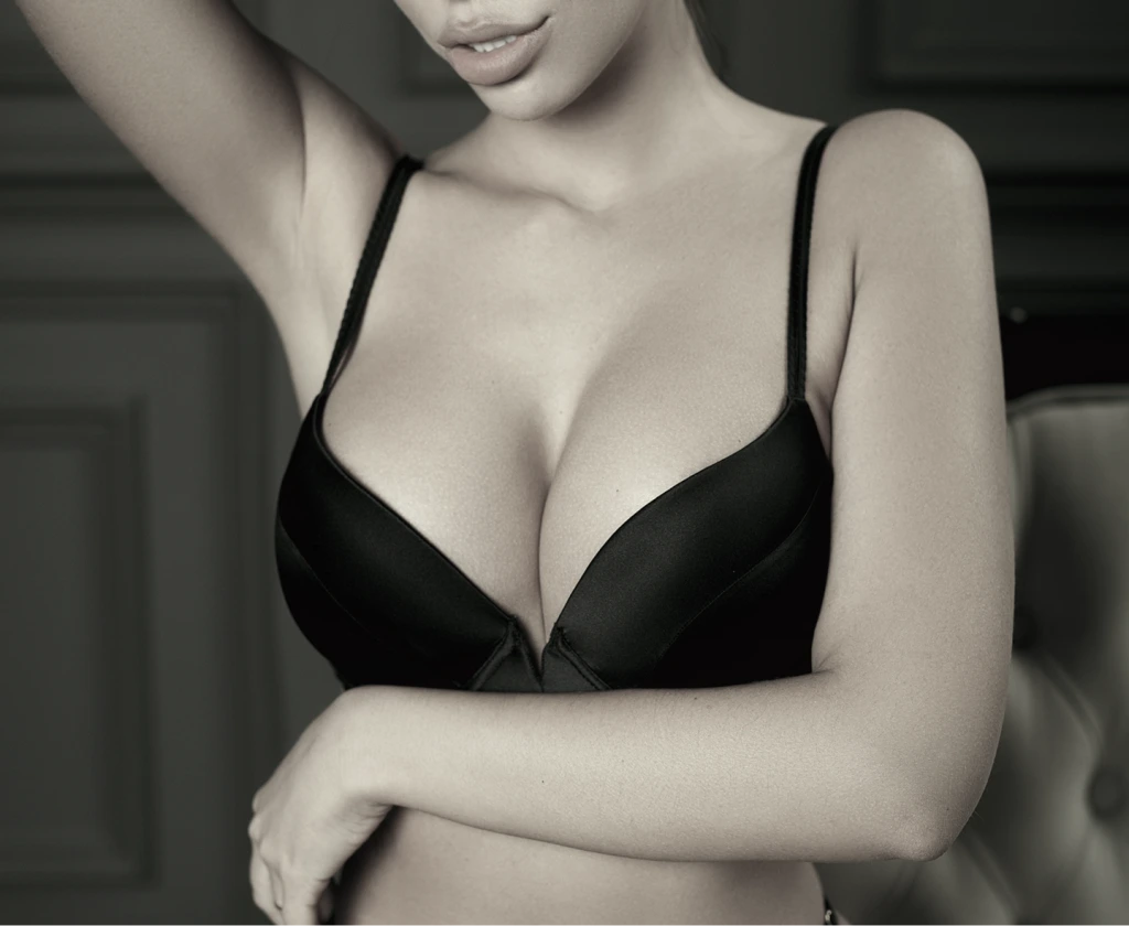 Woman in black bra with arm raised, cropped torso and shoulder view