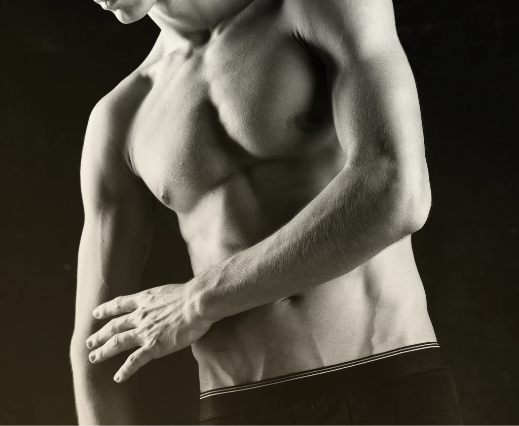 Shirtless man with hand on torso displaying chest and abdominal definition