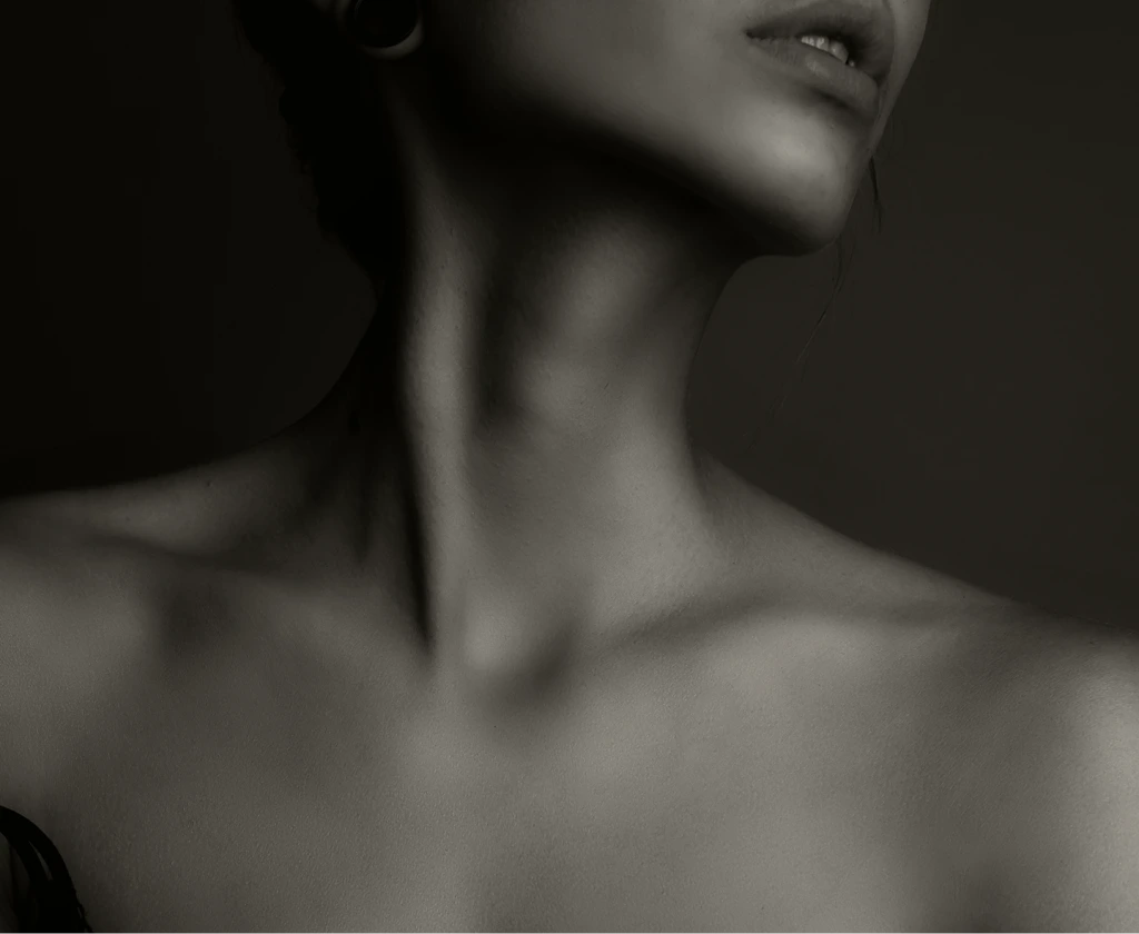 Woman's profile showing neck and jawline against dark background