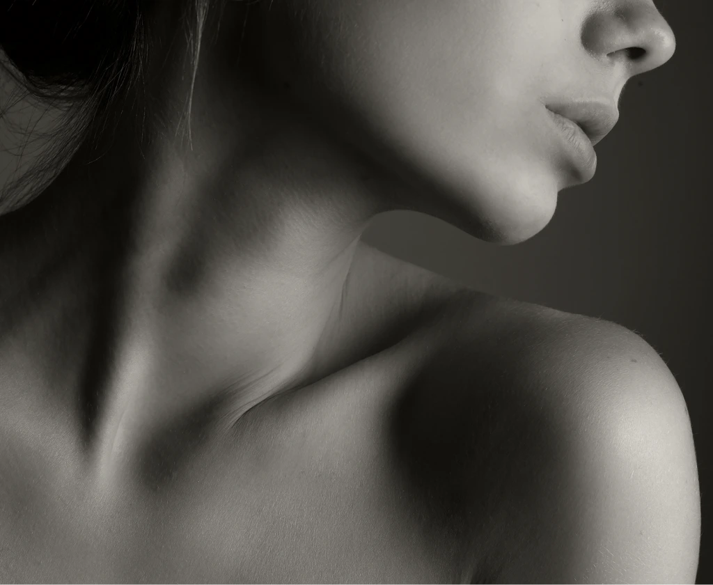 Woman's profile from the side showing neck and shoulder against gray background