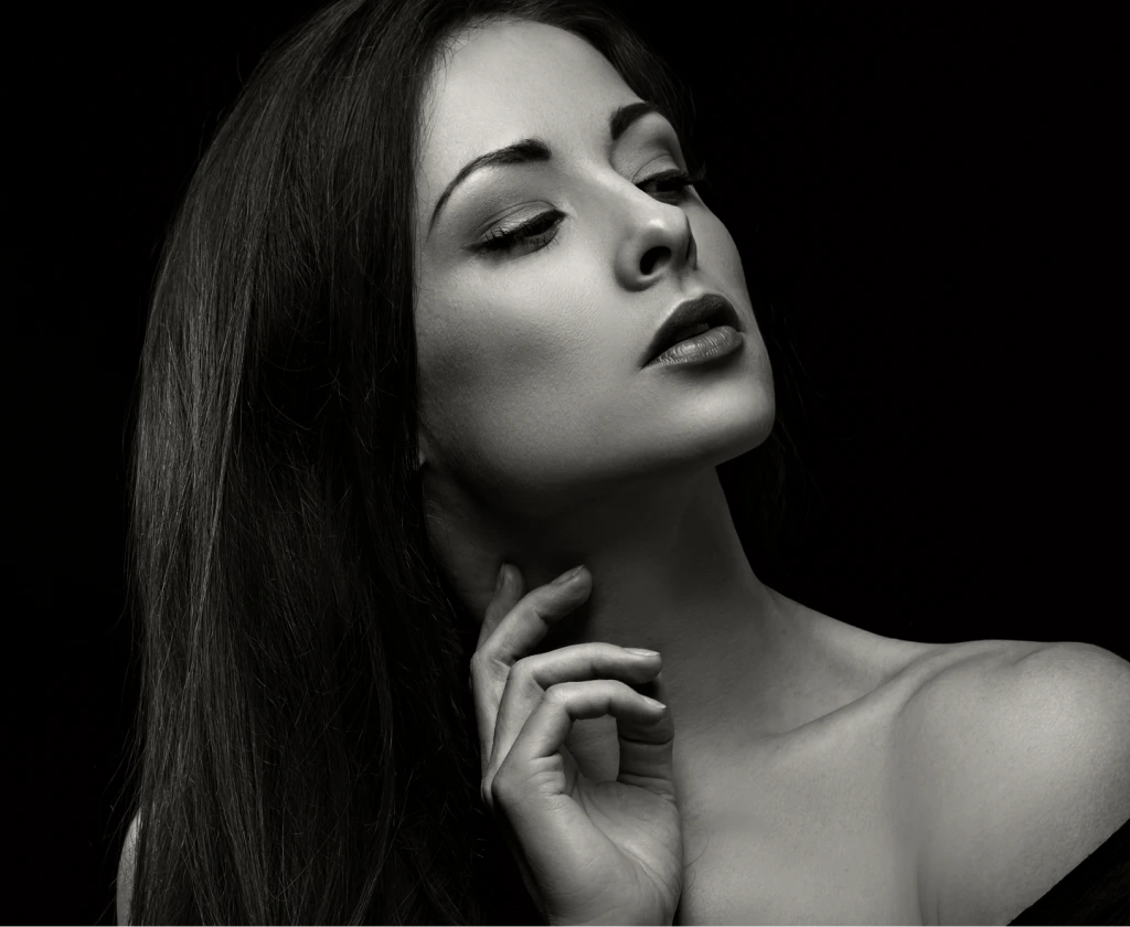 Woman with long dark hair tilting head back with hand near neck