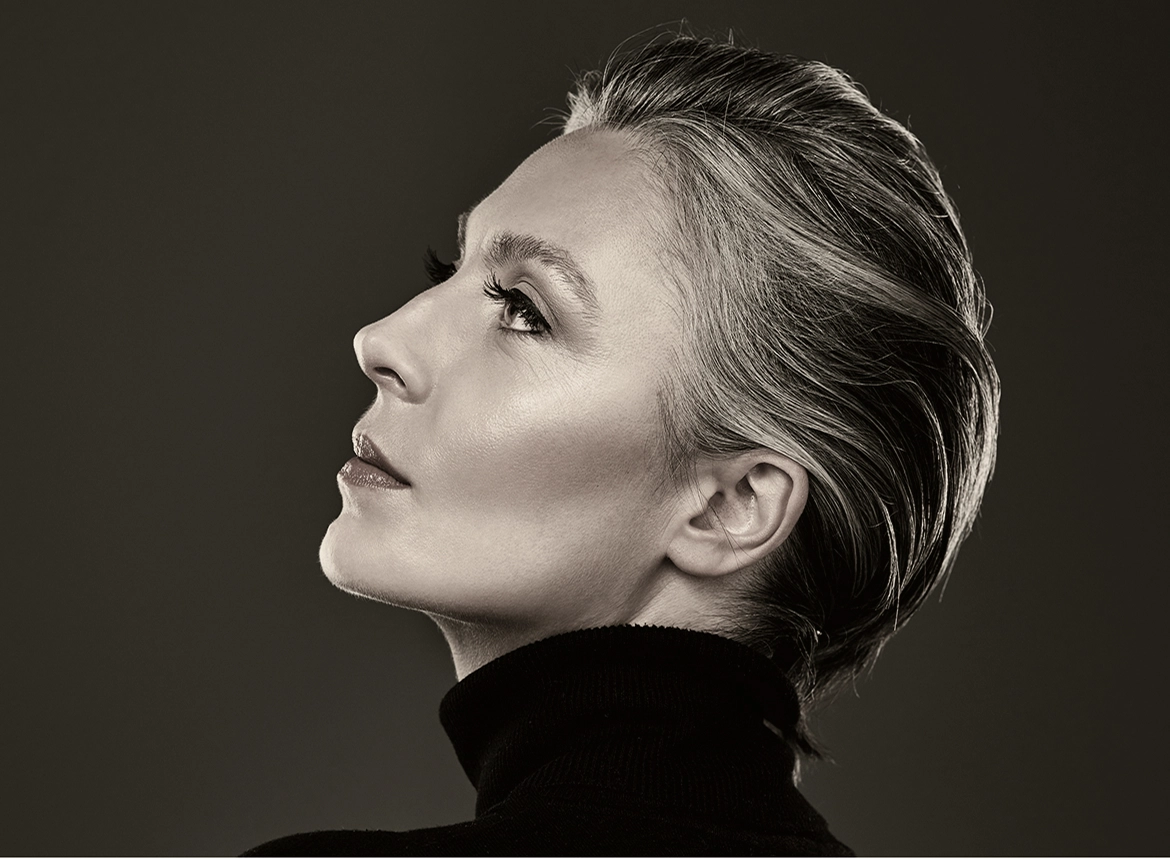 Woman in profile facing left, shown against dark background highlighting facial contours