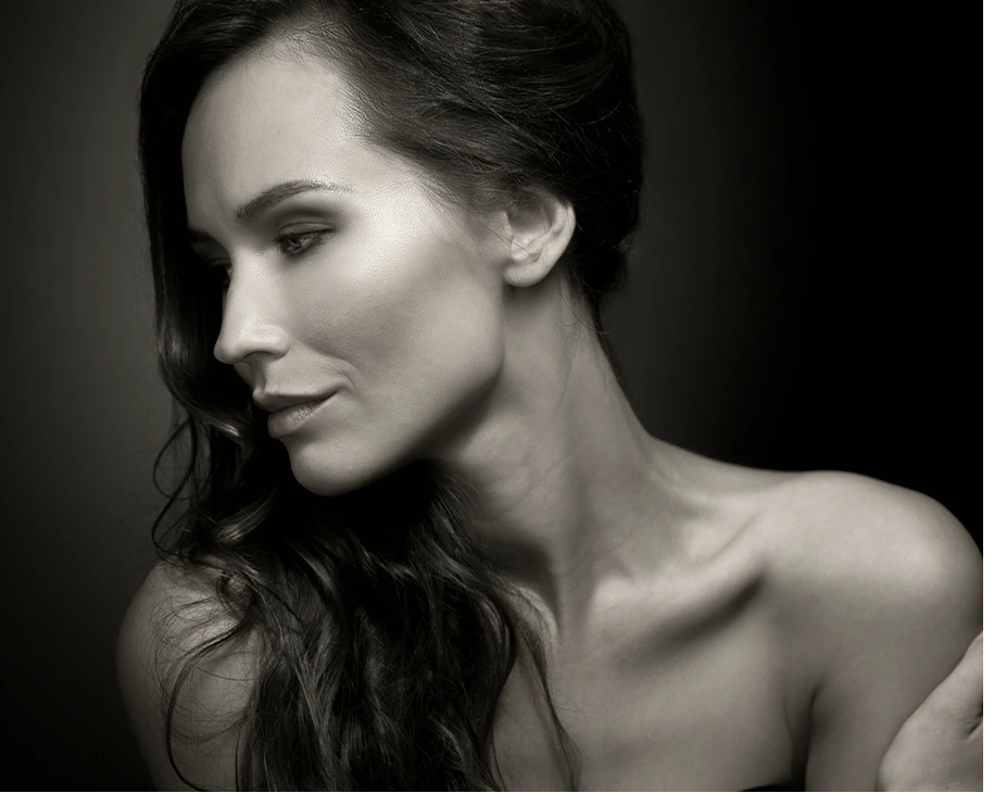 Woman in profile with long dark hair against dark background