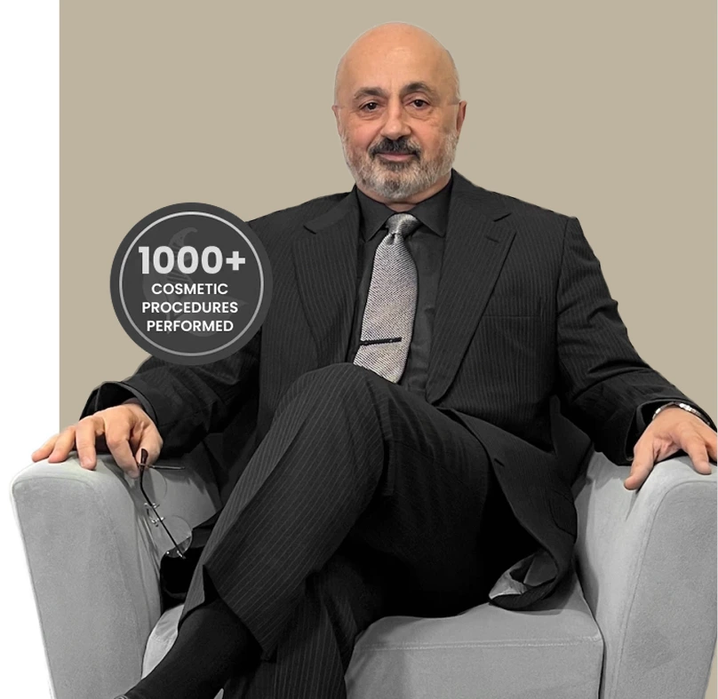 Man in business suit seated in chair with badge reading '1000+ COSMETIC PROCEDURES PERFORMED'