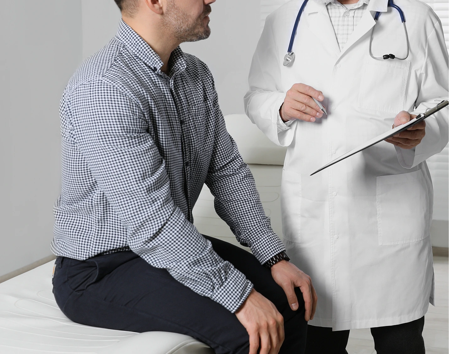Doctor in white coat reviewing clipboard with male patient seated in checkup