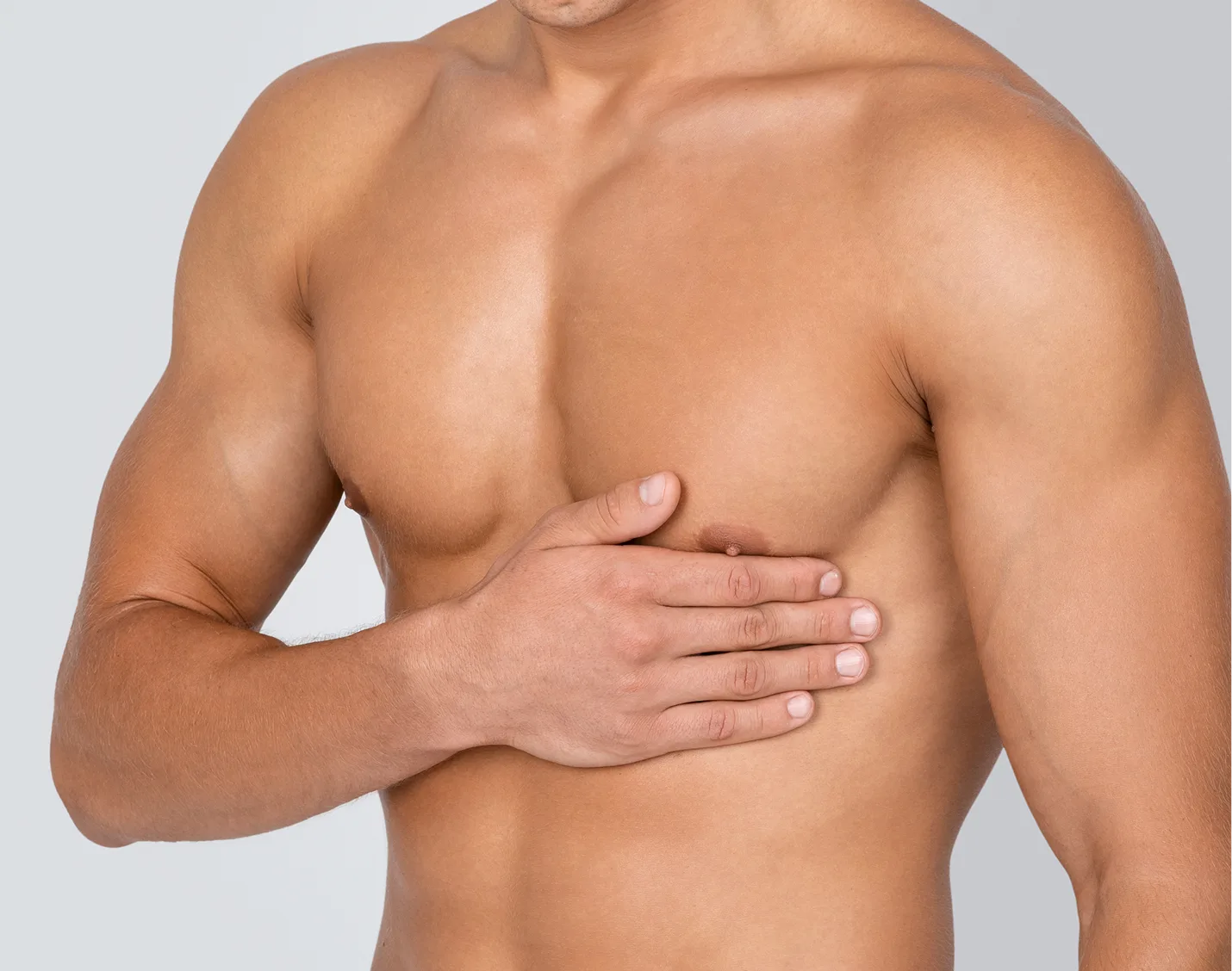 Man with enlarged breast tissue pressing hand against chest, demonstrating gynecomastia condition