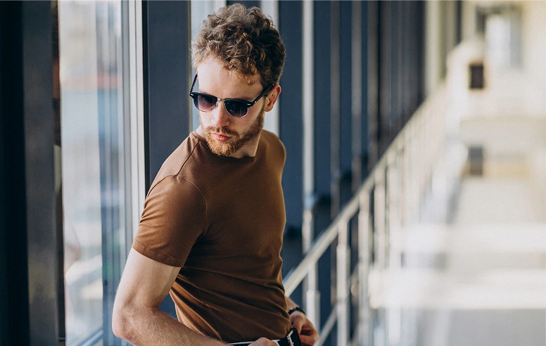 Man in brown shirt wearing sunglasses on urban balcony
