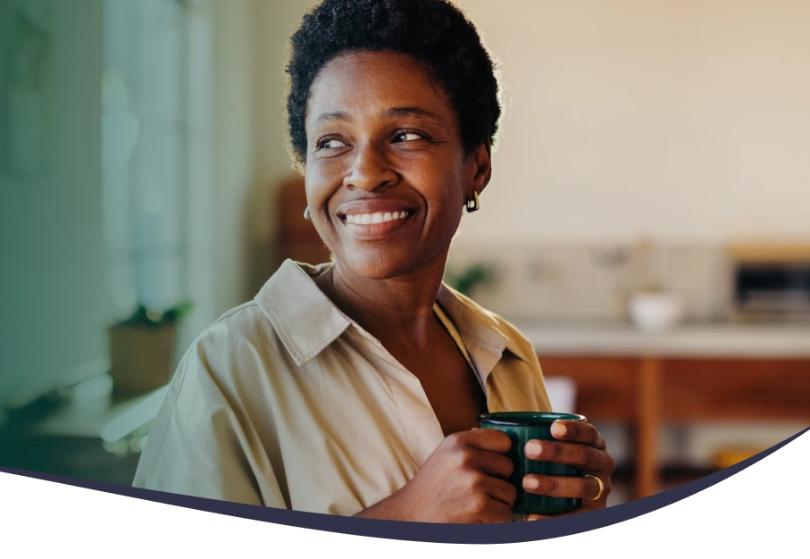 Smiling woman holding a mug in a warm home kitchen