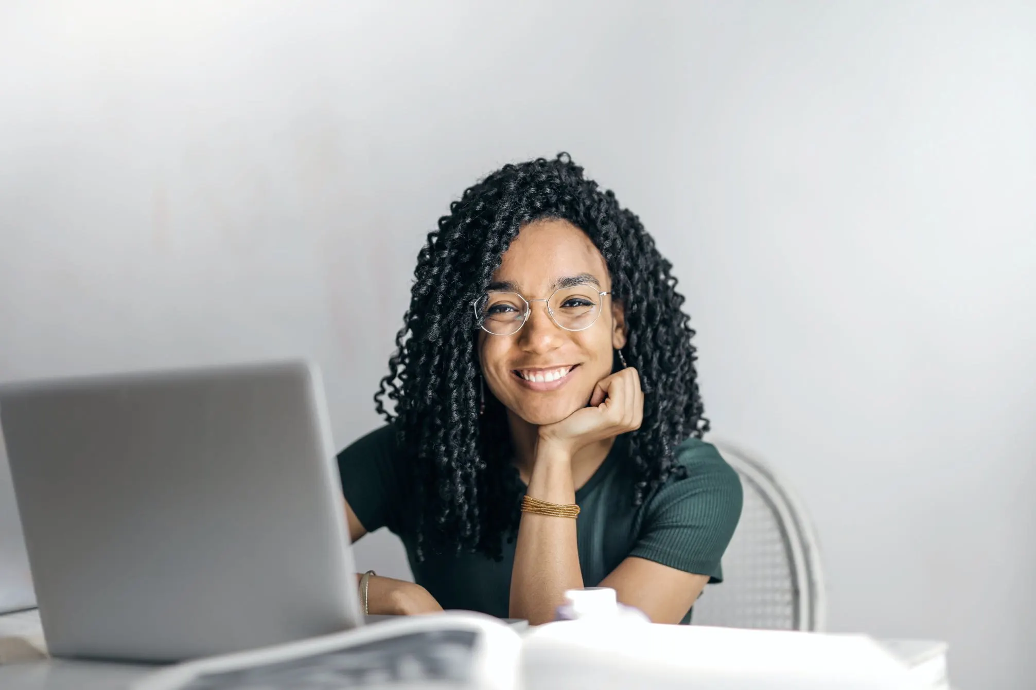 Smiling professional woman with glasses working at a laptop in an office