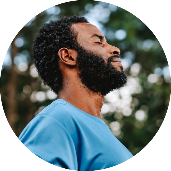 Man in profile outdoors with eyes closed, appearing peaceful and calm