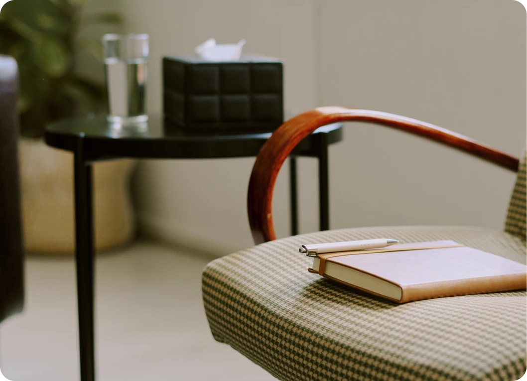 Consultation room with notebook and pen on upholstered chair, water glass and tissue box on side table