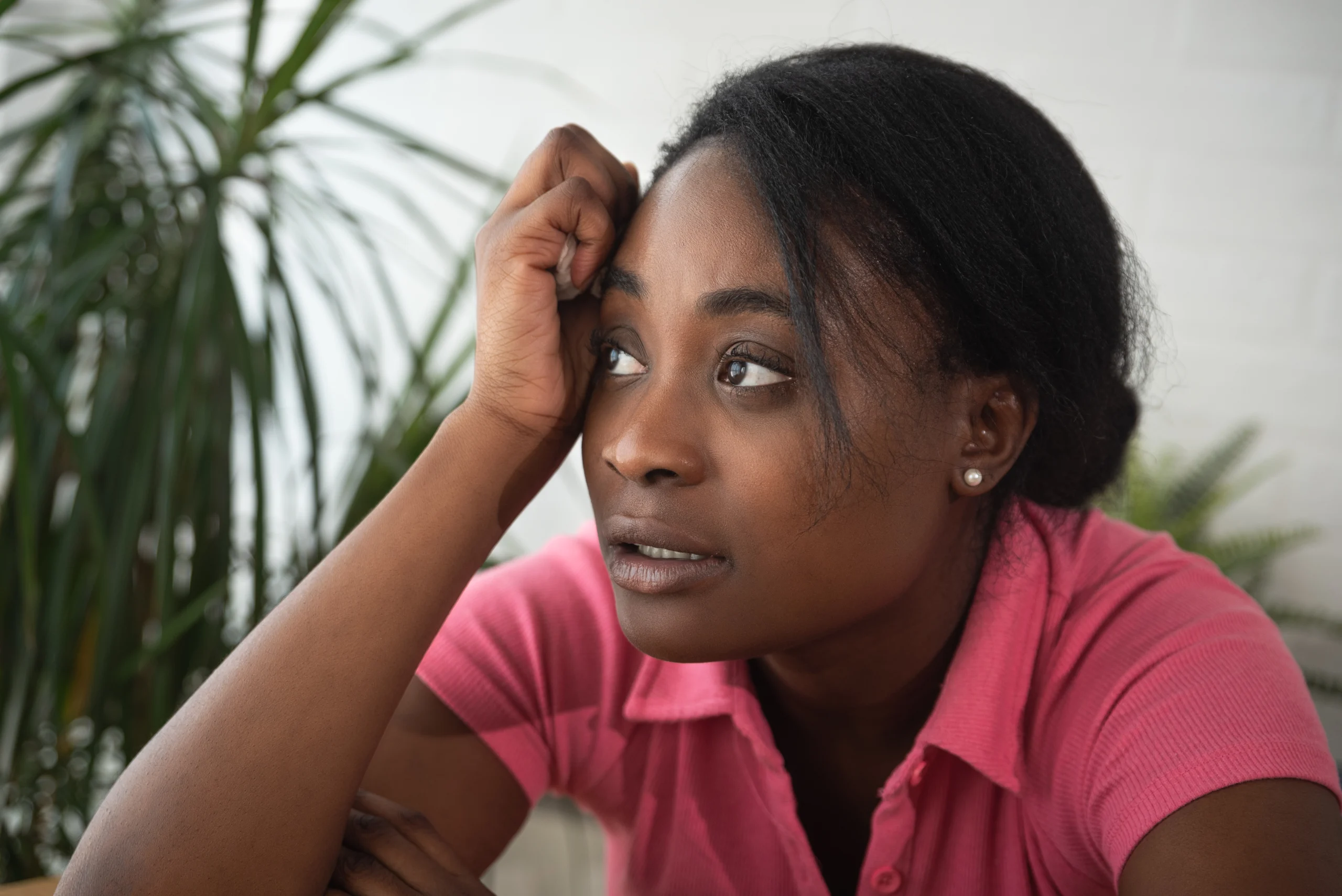 Young African American woman resting her head on her hand with a thoughtful expression