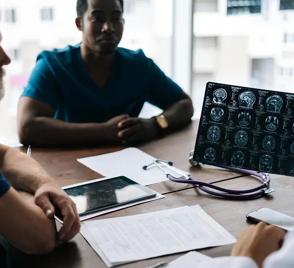 Healthcare providers discussing patient records and brain scan images at a table