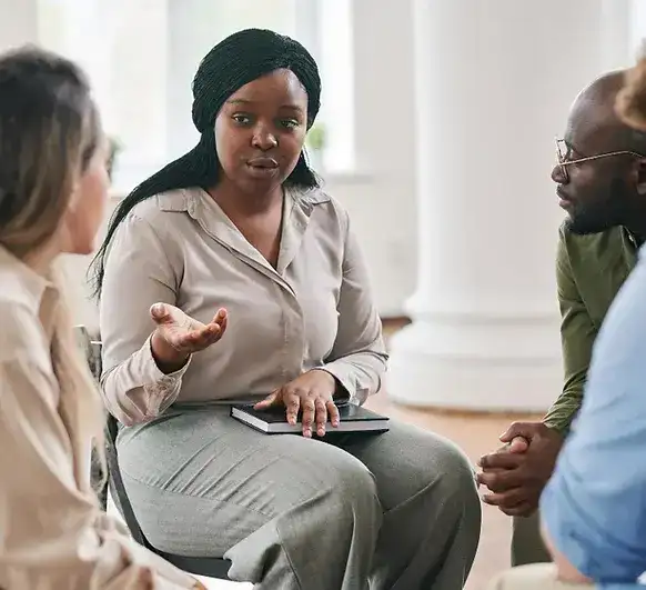 Mental health clinician facilitating a substance abuse treatment discussion with two patients in a clinical setting