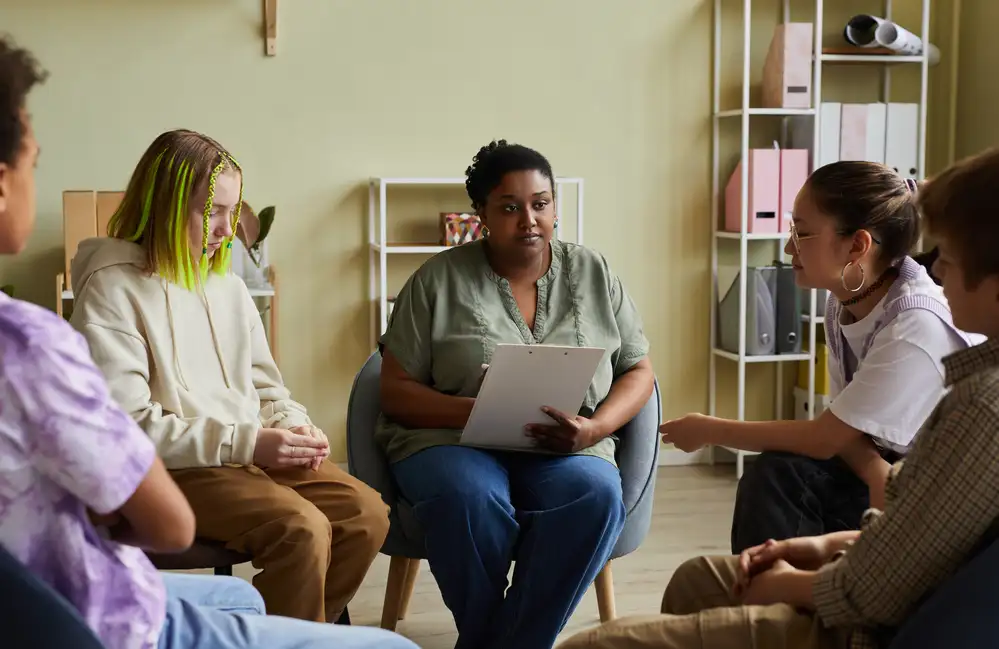 Mental health professional leading a family group therapy session in a calm clinical setting