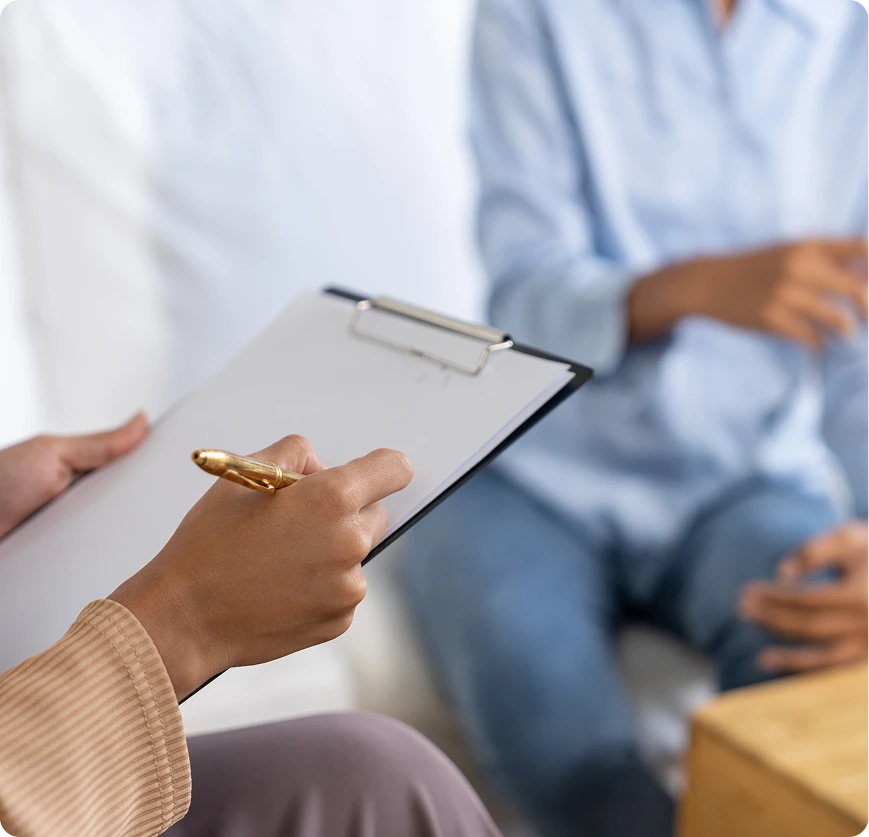 Patient holding a clipboard during a consultation with a healthcare provider in a clinical setting