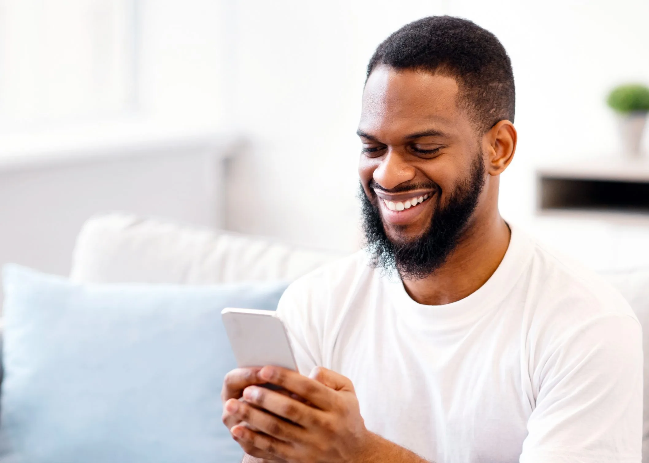 Smiling African American man on his couch looking at results on his phone
